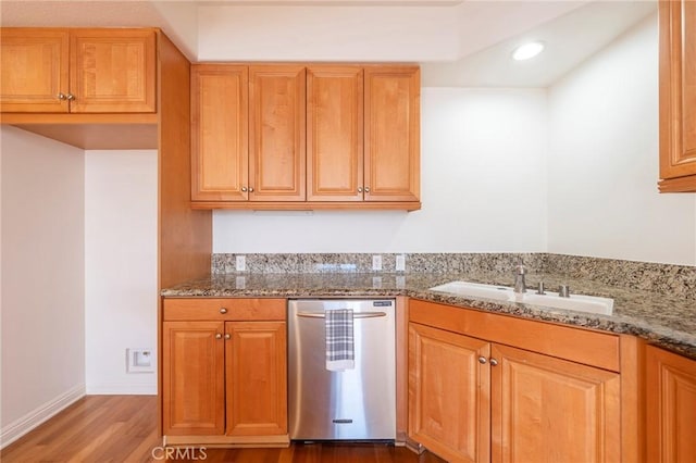 kitchen with hardwood / wood-style flooring, sink, stainless steel dishwasher, and light stone counters