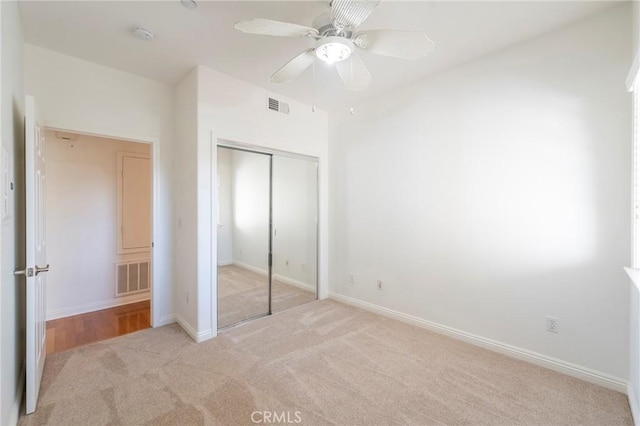 unfurnished bedroom with ceiling fan, light carpet, and a closet