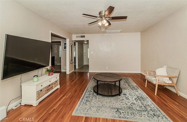 sitting room with ceiling fan, dark hardwood / wood-style flooring, and a textured ceiling