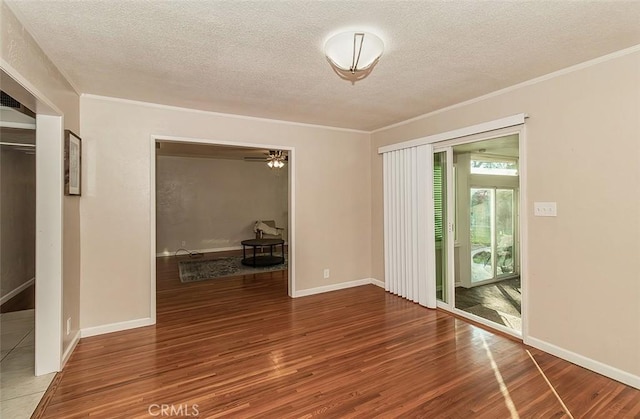 empty room featuring hardwood / wood-style flooring, a textured ceiling, ornamental molding, and ceiling fan