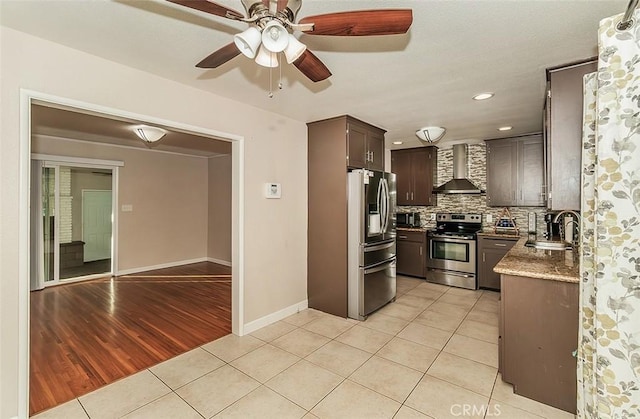 kitchen with appliances with stainless steel finishes, decorative backsplash, light tile patterned flooring, wall chimney exhaust hood, and sink