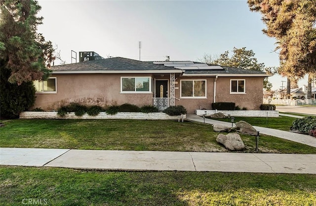 view of front of home with a front yard and solar panels