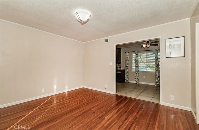 empty room with a textured ceiling, ceiling fan, crown molding, and hardwood / wood-style flooring