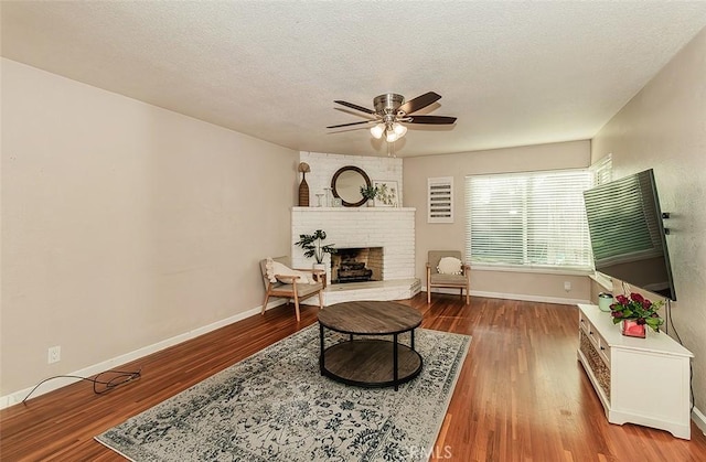 living room with a textured ceiling, ceiling fan, hardwood / wood-style flooring, and a brick fireplace