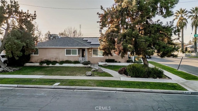 view of front of home with a yard and solar panels