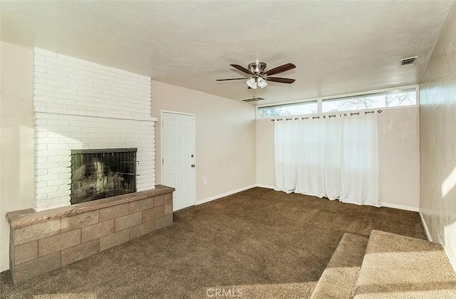 unfurnished living room with ceiling fan, a fireplace, a textured ceiling, and dark colored carpet