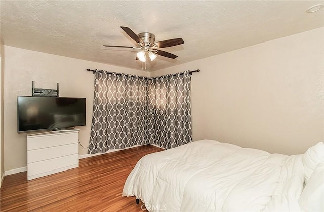 bedroom with a textured ceiling, ceiling fan, and hardwood / wood-style flooring