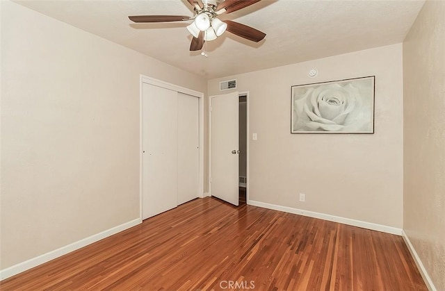 unfurnished bedroom featuring ceiling fan, a closet, and wood-type flooring