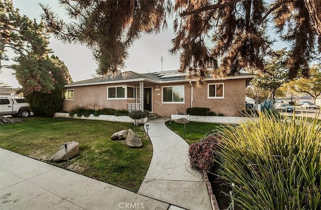 ranch-style home featuring a front yard and solar panels