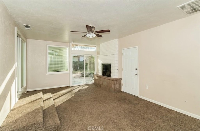 unfurnished living room with ceiling fan, dark carpet, a textured ceiling, and a fireplace