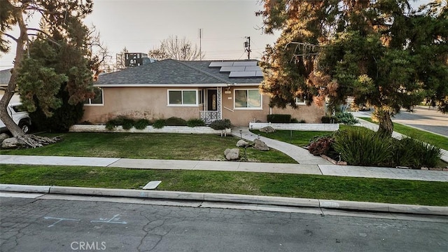 view of front of house with a front lawn and solar panels