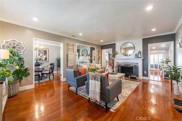 living room with hardwood / wood-style floors, crown molding, and a stone fireplace