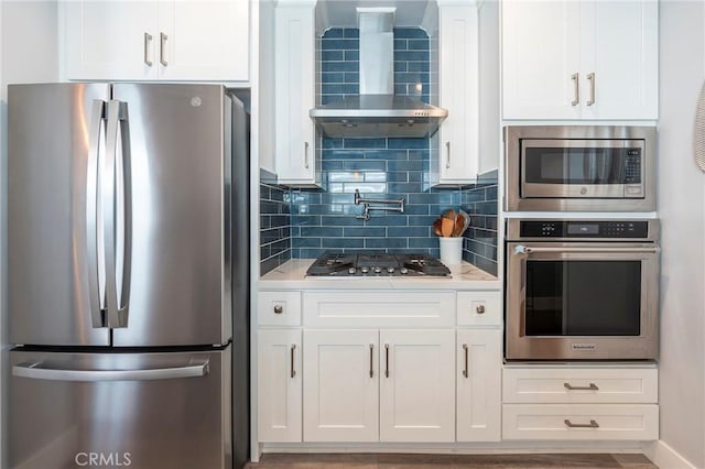 kitchen with white cabinets, appliances with stainless steel finishes, and wall chimney exhaust hood