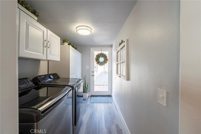 laundry room featuring cabinets, light hardwood / wood-style flooring, and independent washer and dryer