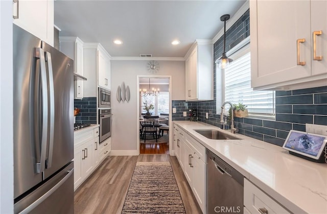 kitchen with decorative light fixtures, sink, stainless steel appliances, and white cabinetry