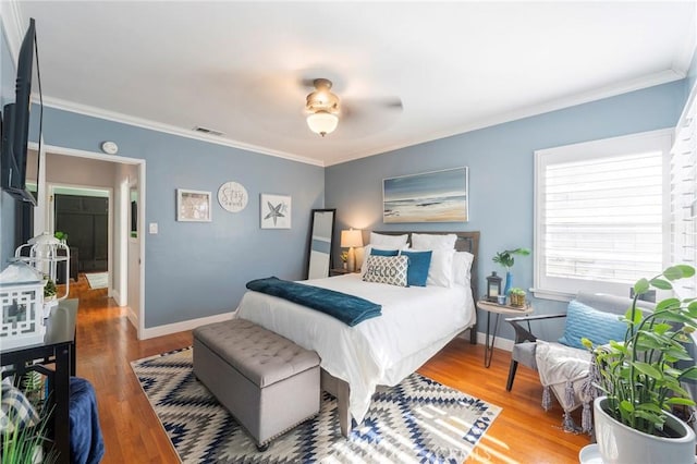 bedroom with ceiling fan, ornamental molding, and hardwood / wood-style flooring