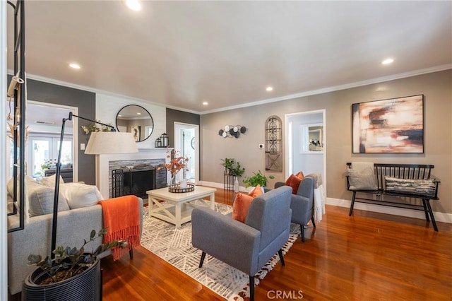 living room featuring wood-type flooring, a stone fireplace, and ornamental molding