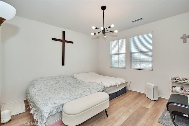 bedroom with a notable chandelier and light wood-type flooring