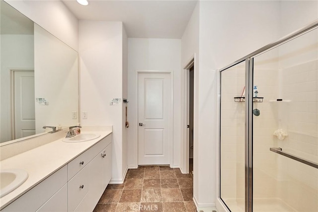 bathroom featuring a shower with door and vanity