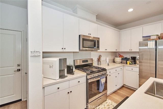 kitchen with light wood-type flooring, appliances with stainless steel finishes, and white cabinets