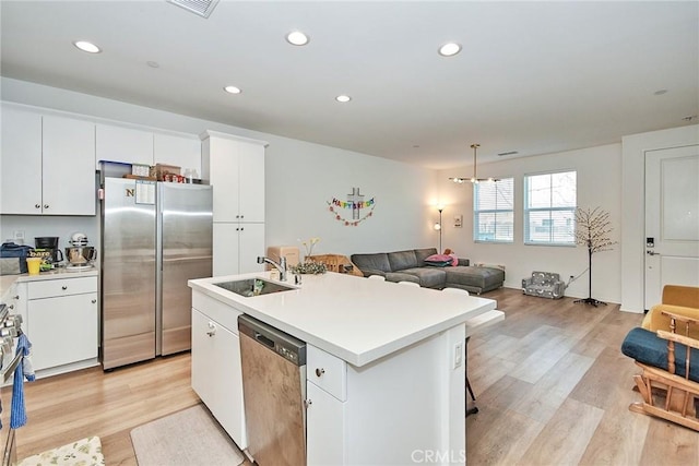 kitchen featuring white cabinets, sink, stainless steel appliances, and a center island with sink