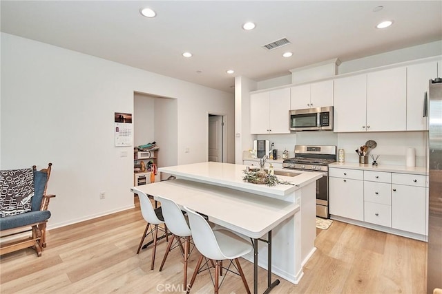 kitchen featuring sink, white cabinetry, a center island with sink, and stainless steel appliances