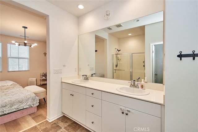 bathroom featuring an enclosed shower, vanity, and an inviting chandelier