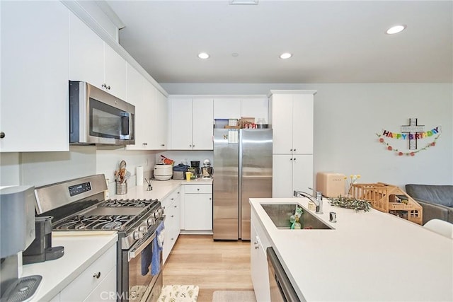 kitchen featuring sink, white cabinets, appliances with stainless steel finishes, and light wood-type flooring