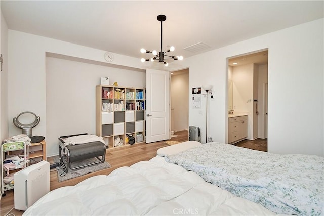 bedroom with connected bathroom, hardwood / wood-style floors, and a notable chandelier