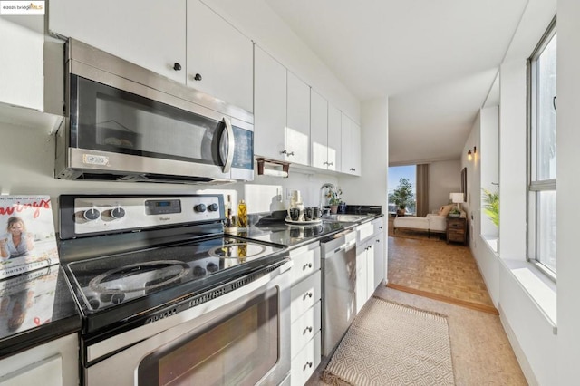 kitchen featuring light parquet flooring, appliances with stainless steel finishes, sink, and white cabinetry