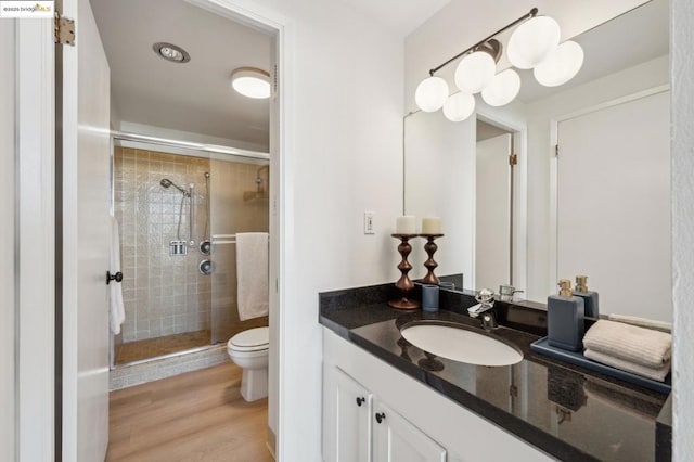 bathroom with hardwood / wood-style floors, an enclosed shower, vanity, and toilet