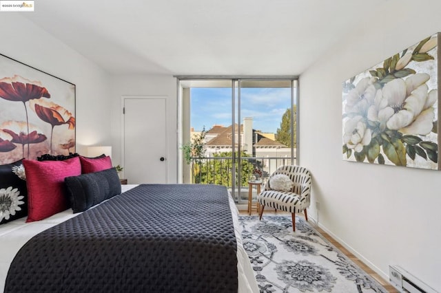 bedroom featuring access to outside, baseboard heating, floor to ceiling windows, and light hardwood / wood-style floors