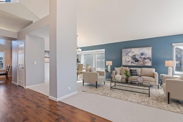 living room featuring vaulted ceiling, dark hardwood / wood-style flooring, and an inviting chandelier