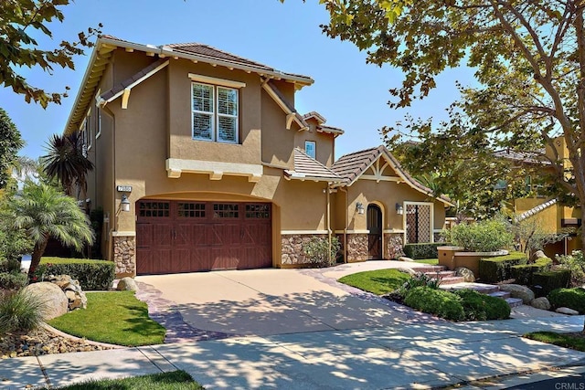 view of front of house featuring driveway, stone siding, a tile roof, an attached garage, and stucco siding