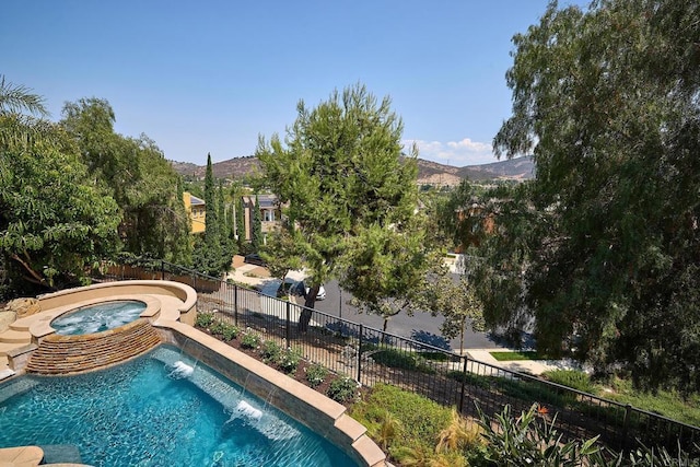 view of swimming pool featuring an in ground hot tub, a fenced backyard, and a mountain view