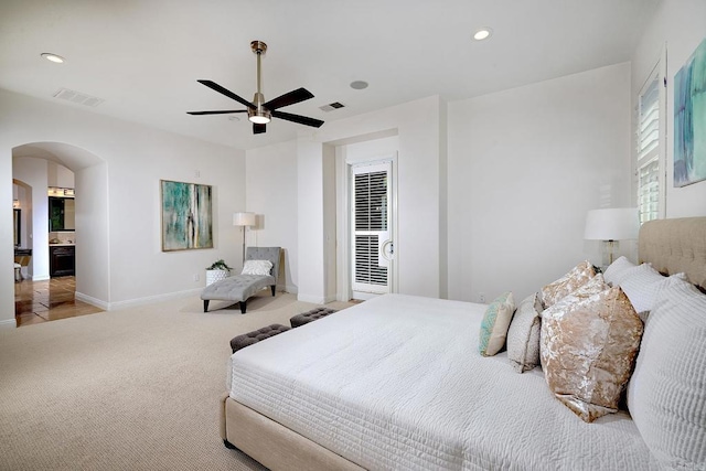 bedroom featuring light carpet, visible vents, arched walkways, and recessed lighting