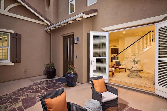 view of exterior entry with stucco siding and a patio