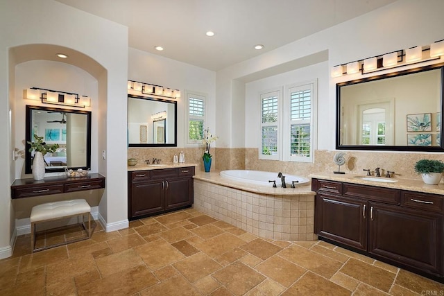 full bathroom featuring a garden tub, a sink, and stone tile floors