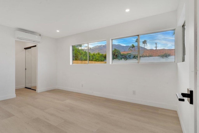 empty room with light wood-type flooring and a wall mounted AC