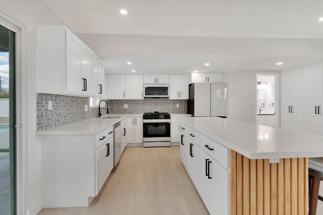 kitchen featuring a kitchen island, a kitchen bar, sink, white appliances, and white cabinetry