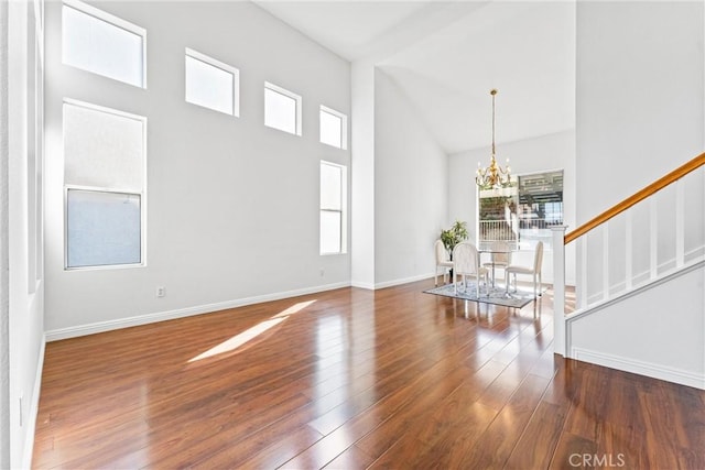 interior space with a high ceiling, dark hardwood / wood-style floors, and an inviting chandelier