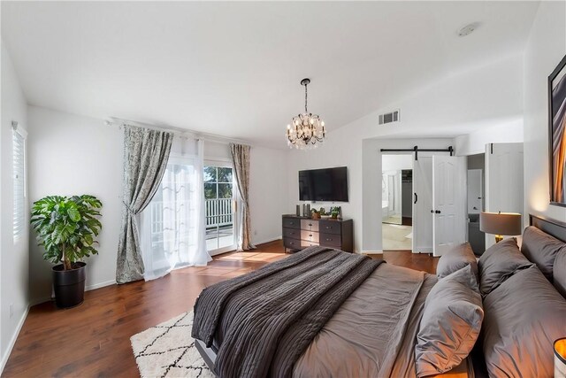 bedroom with lofted ceiling, a barn door, access to exterior, dark wood-type flooring, and connected bathroom