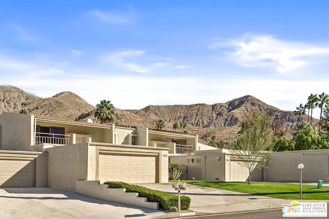 view of front facade with a garage, a mountain view, and a balcony