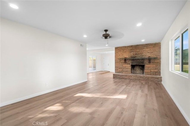 unfurnished living room with light wood-type flooring, ceiling fan, and a fireplace