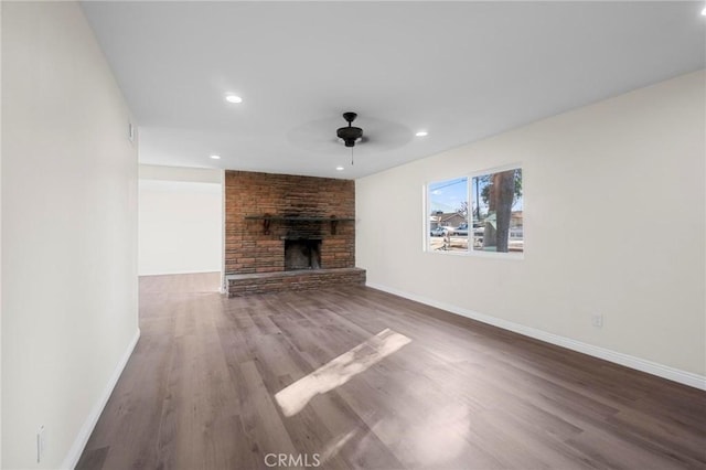 unfurnished living room with ceiling fan, hardwood / wood-style floors, and a stone fireplace