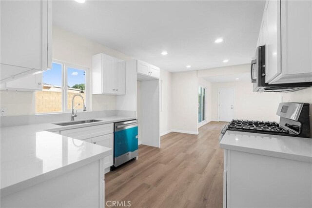 kitchen featuring white cabinets, sink, stainless steel appliances, and light hardwood / wood-style flooring