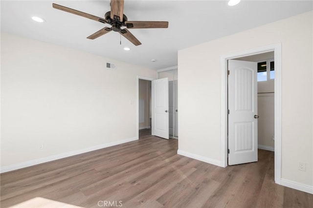 unfurnished bedroom featuring light wood-type flooring, ceiling fan, a closet, and a spacious closet