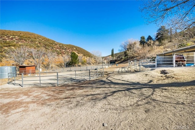 view of yard featuring a mountain view, an outbuilding, and a rural view