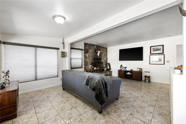 tiled living room featuring a stone fireplace