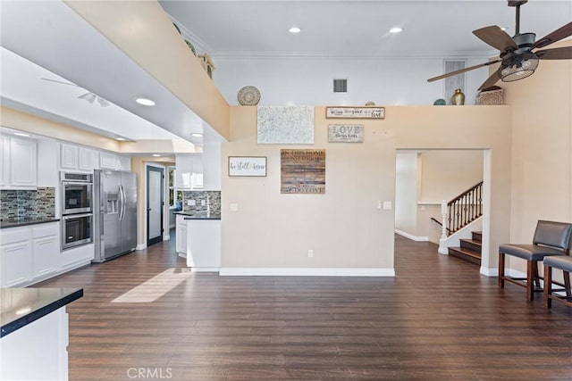 kitchen featuring tasteful backsplash, appliances with stainless steel finishes, white cabinetry, and ornamental molding